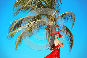 Free Happy Woman Enjoying Nature. Beauty Girl with red hat, summer Outdoor. Freedom concept. Beauty Girl over Sky and Sun.