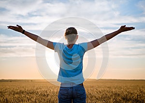 Free Happy Woman Enjoying Nature and Freedom Outdoor. Woman with arms outstretched in a wheat field in sunset.