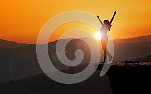 Free and happy woman raises her arms at sunset