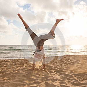 Free Happy Woman Turning Cartwheel Enjoying Sunset on Sandy Beach.