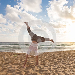 Free Happy Woman Turning Cartwheel Enjoying Sunset on Sandy Beach.