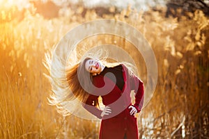 Free happy young woman. Beautiful female with long healthy blowing hair enjoying sun light in park at sunset. Spring