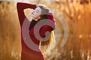 Free happy young woman. Beautiful female with long healthy blowing hair enjoying sun light in park at sunset. Spring
