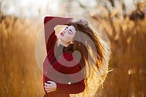 Free happy young woman. Beautiful female with long healthy blowing hair enjoying sun light in park at sunset. Spring