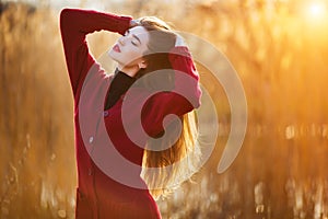 Free happy young woman. Beautiful female with long healthy hair enjoying sun light in park at sunset. Spring, autumn