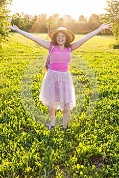 Free happy young woman raising arms watching the sun in the background at sunrise