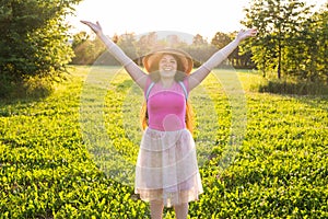 Free happy young woman raising arms watching the sun in the background at sunrise