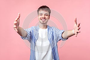 Free hugs. Come here. Portrait of friendly kind brown-haired man stretching hands to embrace. indoor studio shot isolated on pink