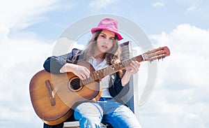 Free music content. Teenage musician playing guitar. Portrait of little kid playing guitar on sky background. summer