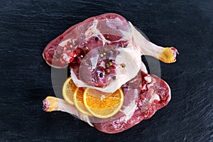 Free range Duck legs with oranges and herbs on old blue stone table. Preparing to cook