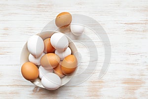 Free-range organic brown and white eggs in bowl on wood background with copy space