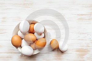 Free-range organic brown and white eggs in bowl on wood background with copy space