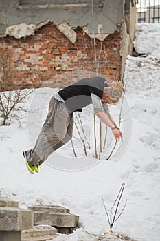 Free-run work out - teenager blonde hair guy training parkour jump flip in the snow covered park photo