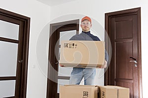 Free shipping concept. Courier delivery man with cardboard box in hands at apartment room of home.
