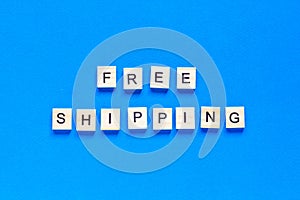 Free shipping lettering in wooden letters on a blue background, top view. Service concept, delivery, promotion, free of charge