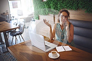 Free time is for making extra money. a young woman using a laptop and smartphone while working at a cafe.