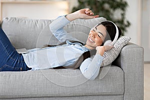 Free Time Relax. Joyful Korean Woman Listening Music In Headphones At Home