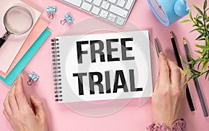 FREE TRIAL text on notebook and hands on pink background, business concept