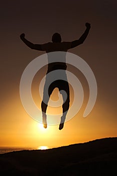 Free and in tune with the world. Silhouette of a man jumping in the air with the sunset in the background.
