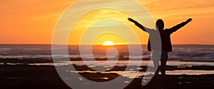 Free woman enjoying freedom on beach at sunset.