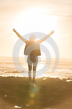 Free woman enjoying freedom on beach at sunset.