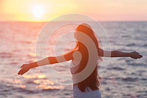 Free woman enjoying freedom feeling happy at beach at sunset.