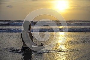 Free woman sitting looking to sea sunset practicing yoga and meditation at beautiful Asian beach