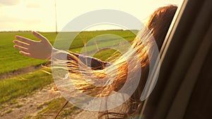 Free woman travels by car catches the wind with her hand from the car window. Girl with long hair is sitting in front