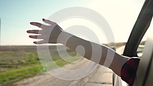 free woman travels by car catches the wind with her hand from the car window. Girl with long hair is sitting in front