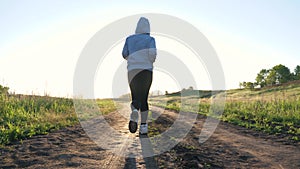 Free young woman is training in summer in the park at dawn. Healthy beautiful girl is engaged in fitness, jogging in