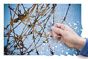 Free yourself from.... Concept image with barbed wire in jigsaw puzzle shape.