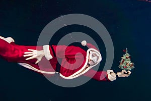 Freediver dressed as Santa Claus swims underwater with a Christmas tree
