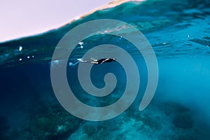 Freediver in wetsuit swimming in the ocean, underwater view