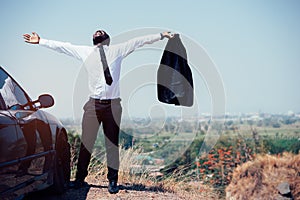 Freedom African businessman take off suit and standing on top of mountain with car