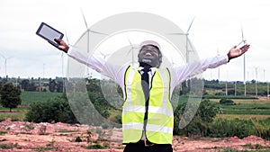 Freedom african engineer standing and hoding laptop with wind turbine.16:9 style photo