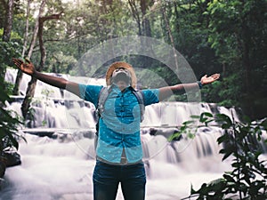 Freedom african traveler man with backpack enjoying amazing tropical waterfall raising hands travel lifestyle and success vacation