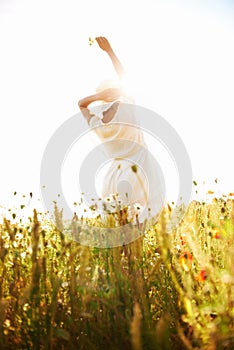 Freedom, back and woman at wheat field with flower in the countryside in summer, vacation or travel. Rear view, person
