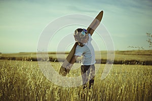 Freedom, Boy playing to be airplane pilot, funny guy with aviator cap and glasses, carries wings made of brown cardboard as an ai