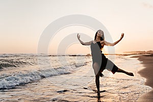 Freedom Chinese woman feeling free dancing at beach sunset.