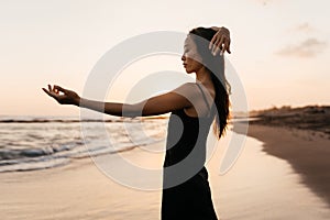 Freedom Chinese woman feeling free dancing at beach sunset.