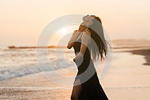 Freedom Chinese woman feeling free dancing at beach sunset.