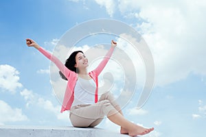 Freedom concept. Enjoyment. Asian young woman relaxing under blu