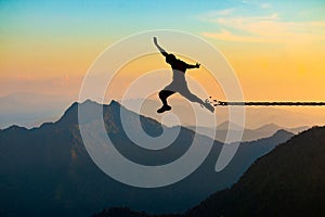 Freedom concept, Silhouette of a man jumping and broken chains at mountain with sunset sky.