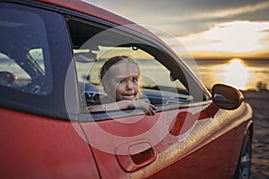 Freedom and family traveler. Girl sitting in the car on the bank of sea after rain