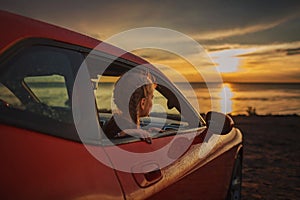 Freedom and family traveler. Girl sitting in the car on the bank of sea after rain