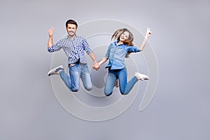Freedom and fun, emotions and feelings. Cheerful and playful couple in casual outfits are jumping and gesturing peace signs indoor