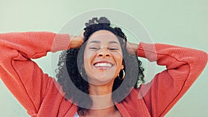 Freedom, hair and fun with a young woman playing with her curly hairstyle and laughing on a green wall background. Happy
