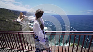 Freedom and happiness concept - joyful woman repenting her hands on the background of the Atlantic Ocean and the coast