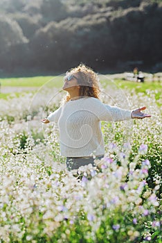 Freedom and happiness enjoying the nature. One woman happy in the middle of a white blossom flowers field opening arms and smiling
