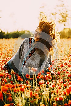 Happy beautiful woman relaxing in poppy flower field.